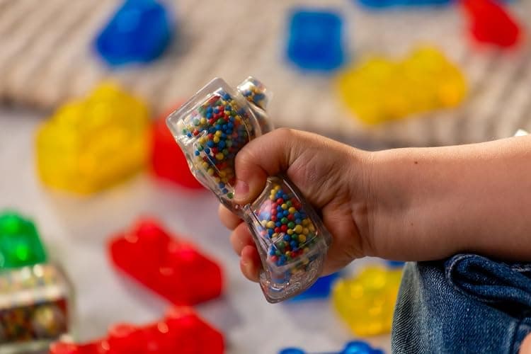 JELLY BLOX- Boite de Rangement + 30 Blocs de Construction Tactiles - Jeu de Construction pour Enfants dès 2 Ans - Expérience Sensorielle avec Blocs Extensibles, Souples et Flexibles - Boite Ouverte thumbnail 2