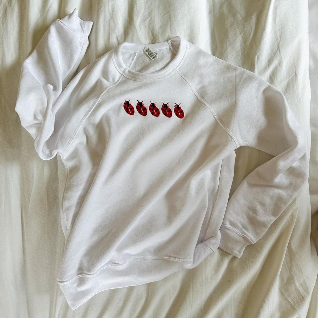 White crew neck sweatshirt with red ladybug design... thumbnail 2